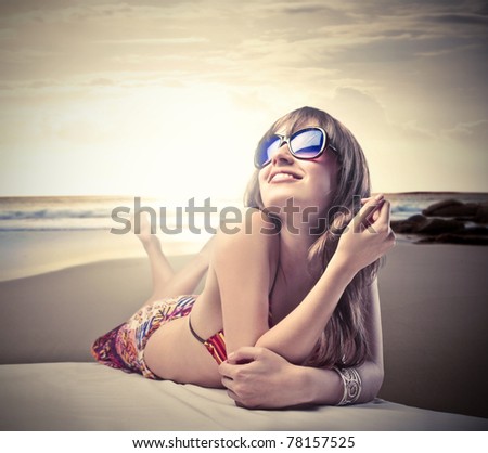 Smiling beautiful woman in bikini lying on a beach