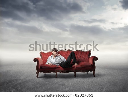 Handsome man lying on a sofa in a desert