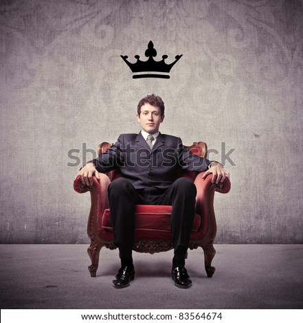 Businessman sitting on an armchair with a crown over his head