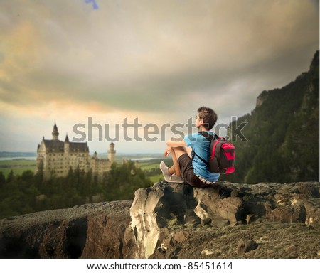 Young explorer sitting on a rock in front of a fairy tale castle