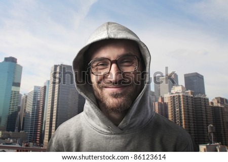 Smiling young man wearing a hood with cityscape in the background