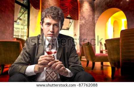 Young man sitting in a lounge bar and holding a glass of wine