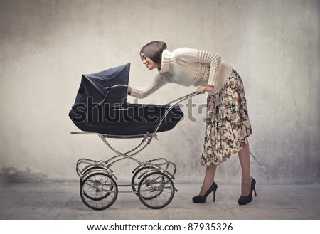 Young mother cuddling her baby lying in a pram