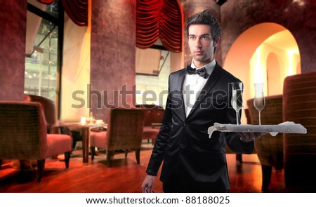 Handsome waiter serving wine glasses in a lounge bar