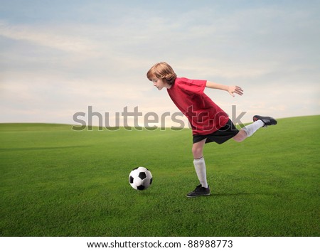 Child playing football on a meadow