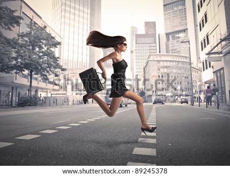 Beautiful elegant woman running on a city street