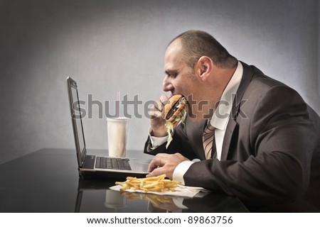 Fat businessman eating junk food while working