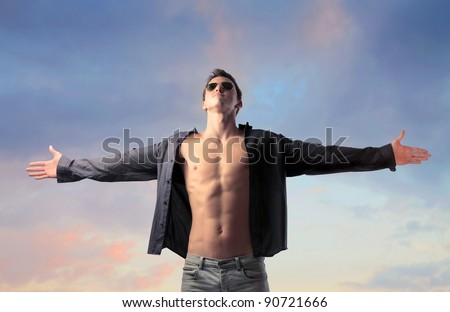 Handsome young man with open shirt stretching out his arms