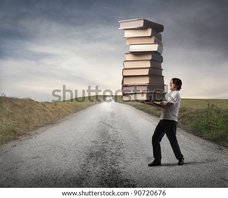 Man carrying a stack of books on a countryside road