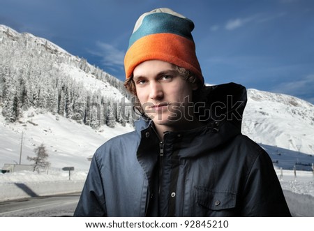Handsome young man in winter clothes and mountains in the background