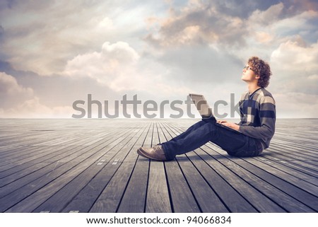 Young man sitting on a parquet floor and using a laptop