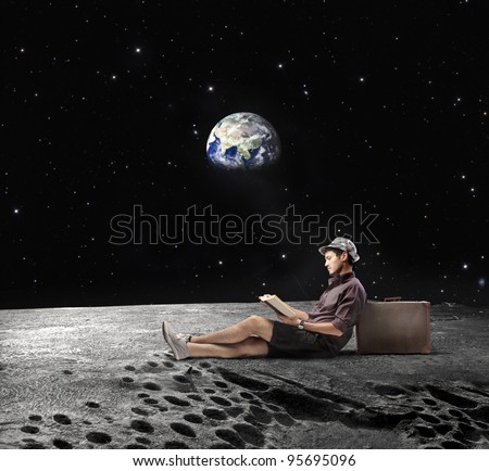 Young man sitting on the Moon and reading a book with Earth in the background \