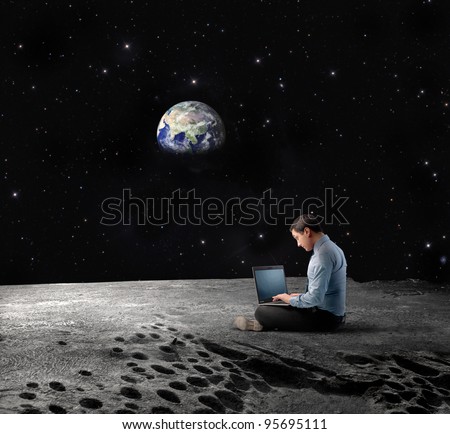 Businessman sitting on the Moon and using a laptop with Earth in the background \