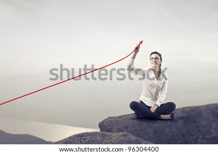 Smiling businesswoman sitting on a rock over a lake and charting a graph with positive trend