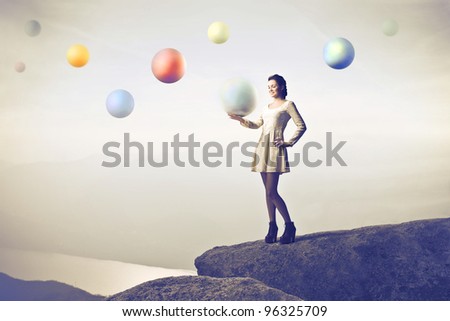 Beautiful woman on a rock over a lake holding a crystal ball with other spheres in the background