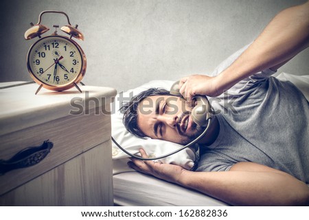 tired man in the bed talking on the phone