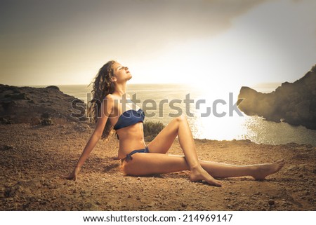 young beautiful woman lying on the rocks at the sunset