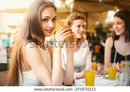 Charming girl sitting at a cafe with her friends