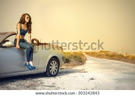 Girl sitting on a car in the countryside