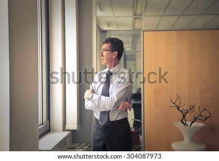 Businessman standing in his office looking out of the window
