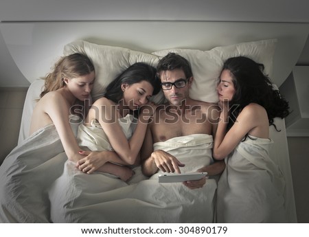 Man using a tablet while sleeping with three women