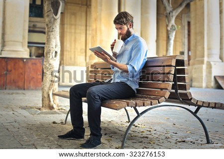 Man sitting on a bench watching a video on a tablet