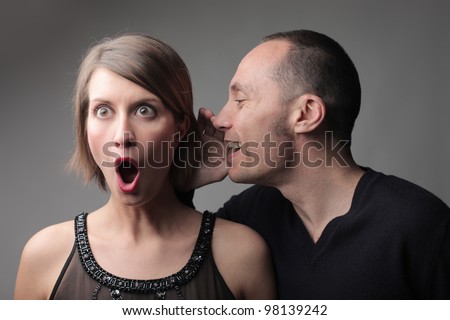 Man telling an astonished woman a secret