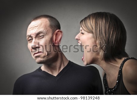 Angry woman screaming against her husband with his face deformed by the power of the scream