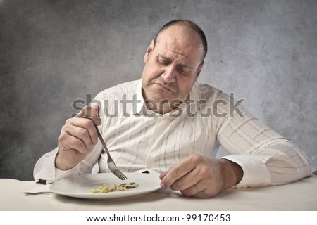 Disappointed fat man eating vegetables
