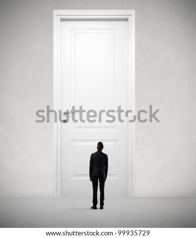Tiny businessman standing in front of a giant door