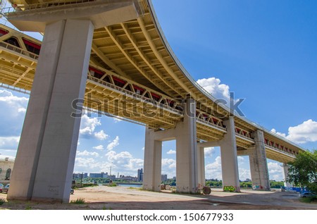 View of the bridge (viaduct) from below against the blue sky with clouds/Beneath the bridge