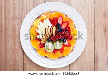 Top view of a delicious Fruit Tart placed in a dish on a wooden table