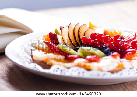 Delicious Fruit Tart. View of a delicious Fruit Tart placed in a dish on a wooden table and in the background a notepad for recipes