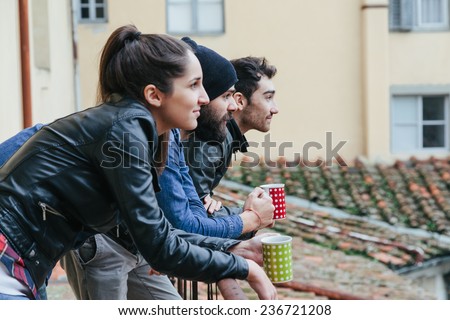 Coffee break. Three friends drinking a hot drink on the terrace on a winter day.