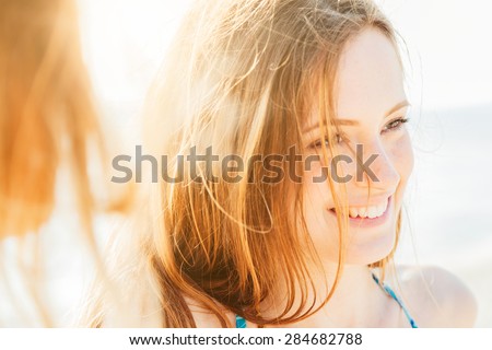 Portrait of a beautiful woman on the beach at sunset. Close-up while smiling and joking with friends after a day of relaxation and fun in the summer break.