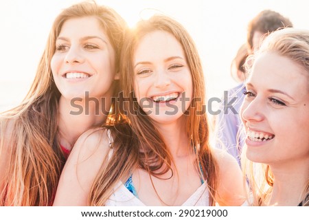 A group of friends, two men and three women, meets and have fun on the beach at sunset