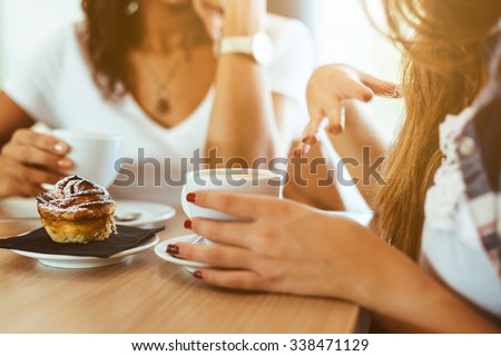 Two young and beautiful women meet at the bar for a cappuccino and to chat. A woman speaks gesturing while the other is listening