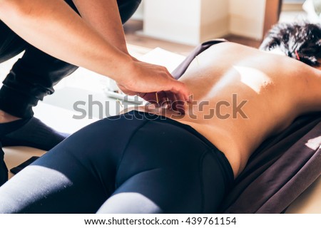 Acupuncture session in a Japanese medical study. A young woman is lying on a mat on the ground while the operator inserts the needles in the back of the patient