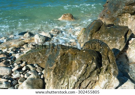 The peninsula of Crimea. Rocky coast in the ancient city of Hersonissos. Sea coast on the Black Sea, large and small pebbles, large boulders, sea waves