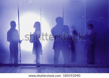 group of colleagues standing against window in office and speaking