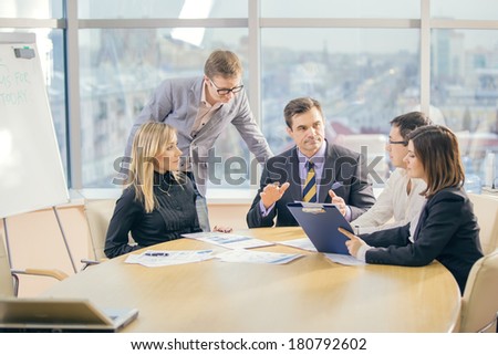 team of five business people discussing an important question at briefing