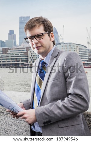 The businessman on the street, background skyscrapers London,  looks documents