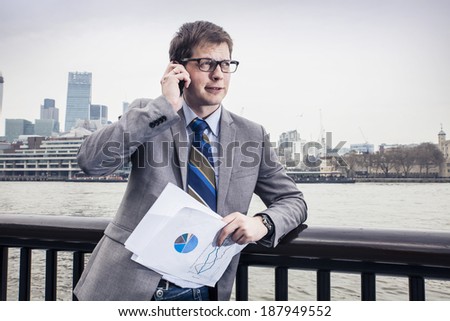 The businessman on the street, background skyscrapers London.  speaks on the smartphone