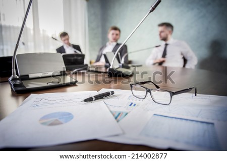 financial chart near dollars seen by unfocused glasses ( colleagues meeting to discuss their future financial plans only silhouettes being viewed )