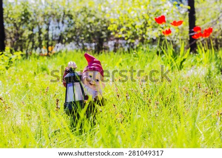 garden gnome - lamp standing on the grass in the garden amid the flowers