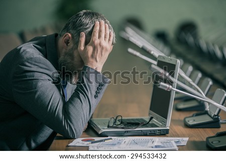 businessman in a panic and depression has her head  	\
on the backdrop of the conference hall in the green range
