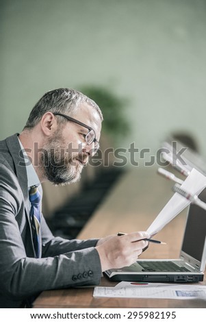 businessman with big beard holding financial statements in the office