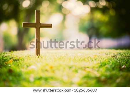 The cross standing on meadow sunset and bokeh background.Cross on a hill as the morning sun comes up for the day.The cross symbol for Jesus christ.Christianity, religious, faith, Jesus or belief.