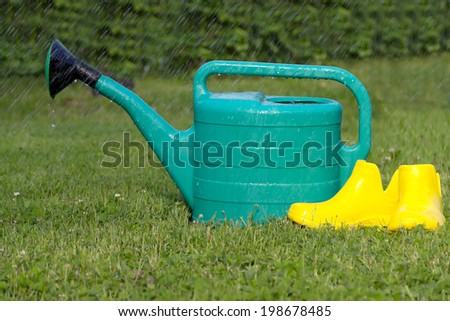 Plastic watering can yellow rubber boots mown lawn grass summer rain