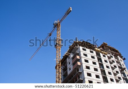 House under construction with construction crane against a clean blue sky